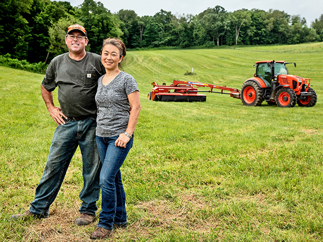 Kenny and Natsuko Merrick stand in front of their original hay meadow. They have restored the soils with no-till and cover crops. (DTN/Progressive Farmer photo by Jodi Miller)